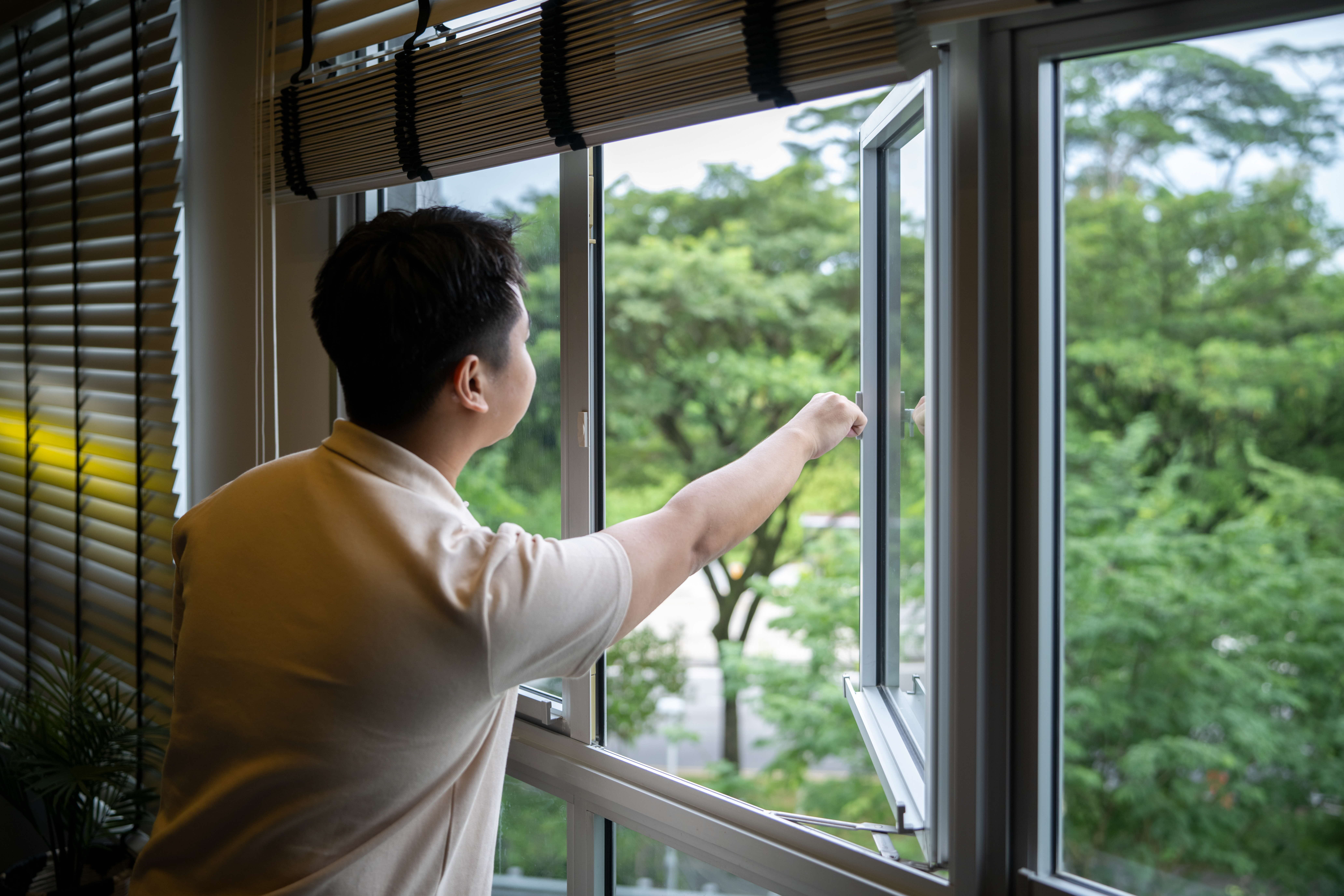 A man opening the window in his home